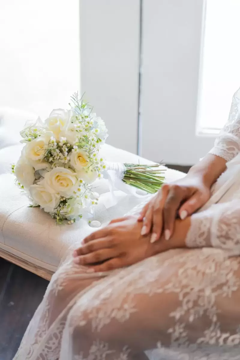 Ảnh cưới Sài Gòn phong cách Hàn Quốc: đôi tay cô dâu đặt cạnh bó hoa hồng trắng bên cửa sổ