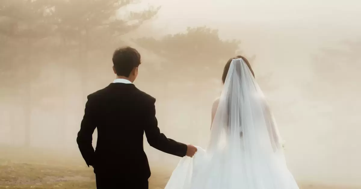 Ảnh cưới Đà Lạt phong cách Hàn Quốc: cô dâu voan trắng và chú rể vest đen quay lưng đi trong sương vàng nhạt