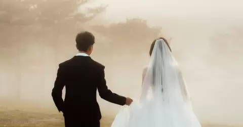 Ảnh cưới Đà Lạt phong cách Hàn Quốc: cô dâu voan trắng và chú rể vest đen quay lưng đi trong sương vàng nhạt