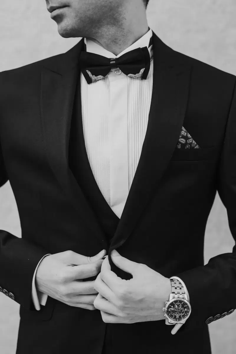 Vest xanh đen Đêm Muộn – váy cưới và trang phục cưới tại NHÂN DUYÊN: chú rể vest đen nơ đeo cổ chỉnh áo, nền sáng