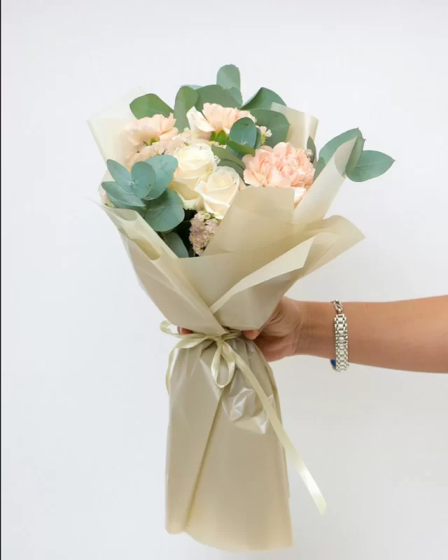 Bó hoa pastel hồng kem gói giấy, gồm hồng, mẫu đơn và lisianthus