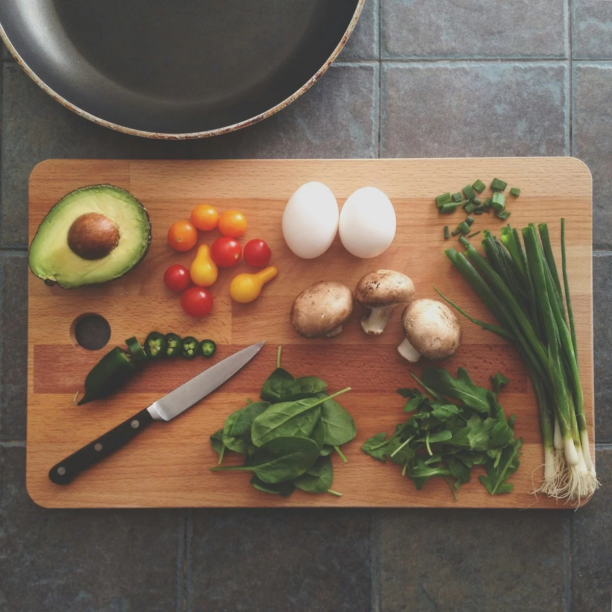Bơ, cà chua bi, trứng, nấm và rau xanh bày trên thớt gỗ cho gói ăn healthy