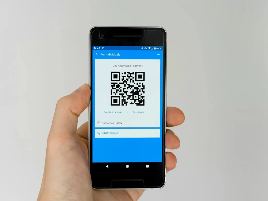 Bàn tay cầm điện thoại hiển thị mã QR để quét truy xuất nguồn gốc rau
