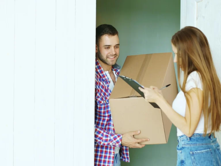 Người giao hàng trao thùng carton cho khách hàng ngay trước cửa nhà