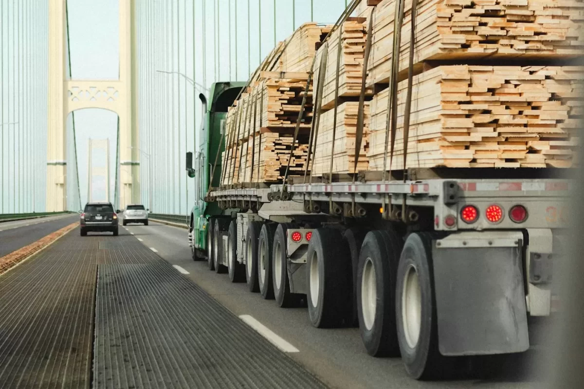 Xe đầu kéo rơ moóc chở các kiện gỗ xếp cao chạy trên đường