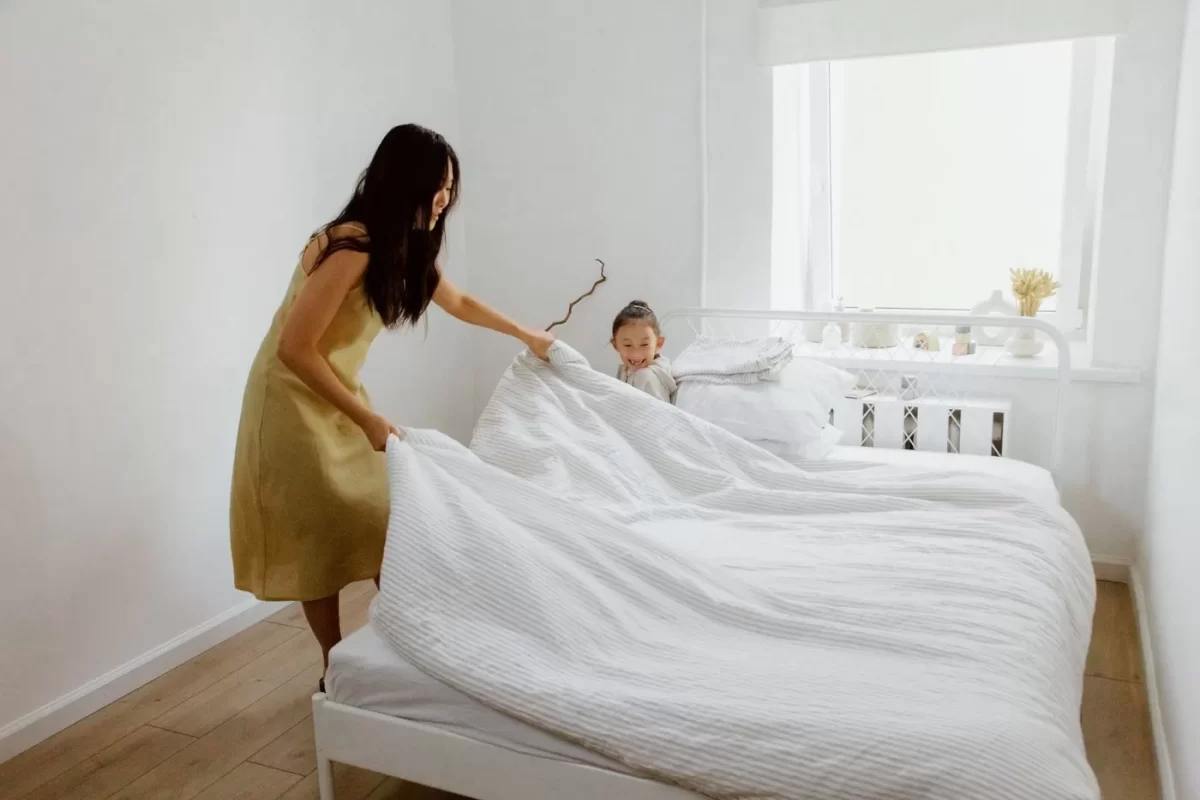 Hai tay trải ga trắng lên chiếc giường để thay đồ ngủ