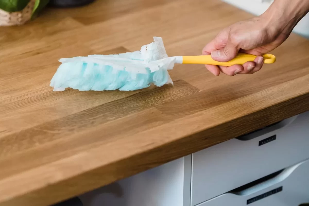Bàn làm việc gỗ được lau bụi bằng chổi lông xanh