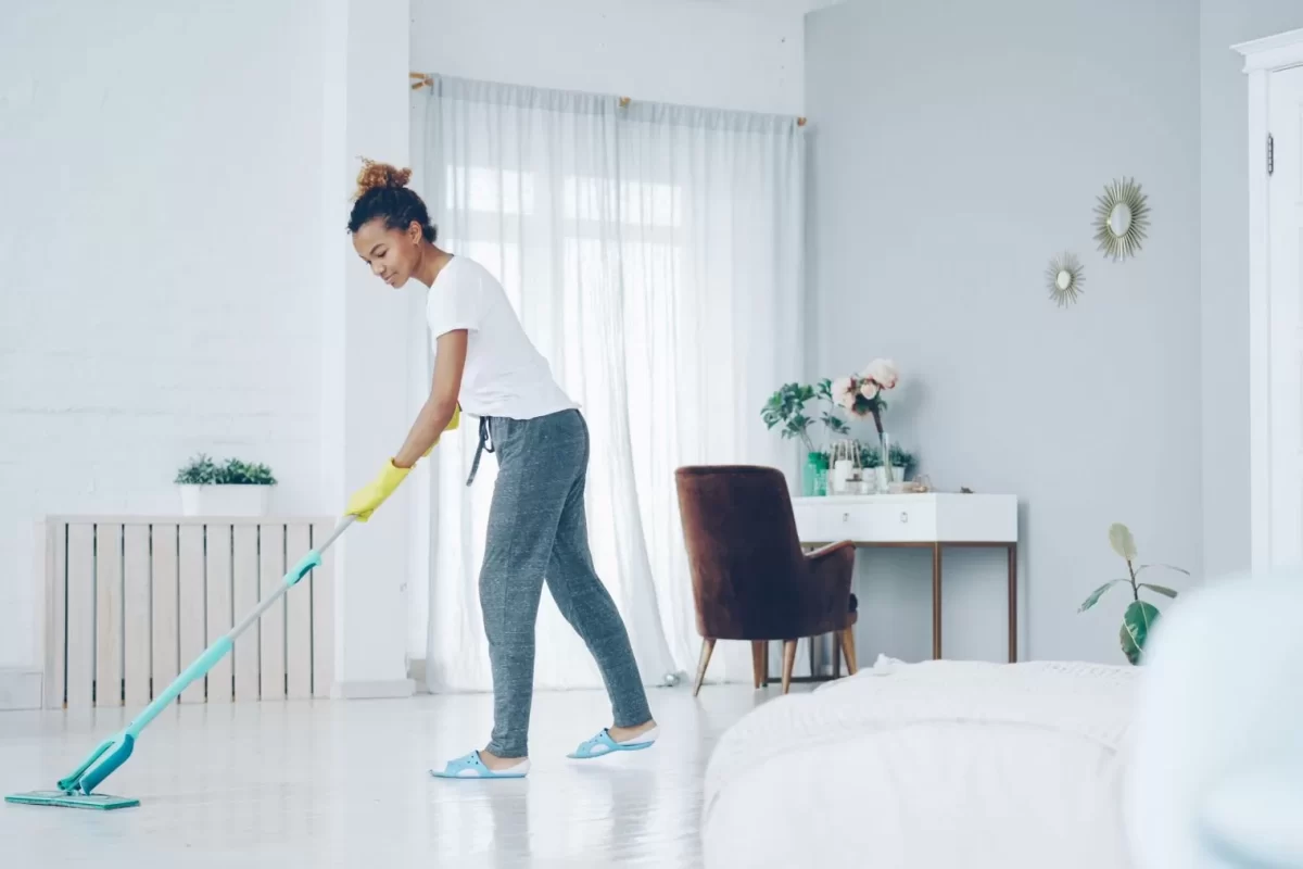 Người đang lau sàn phòng khách sáng sủa bằng cây lau nhà