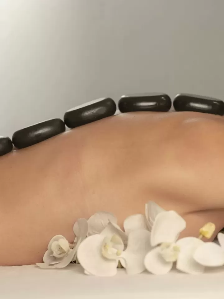 Đá đen và hoa lan trắng đặt trên lưng khách nằm thư giãn