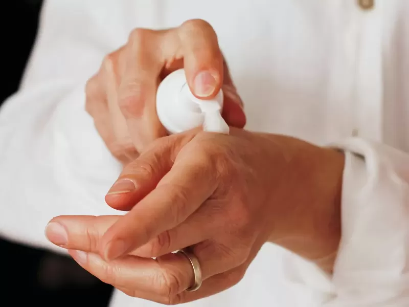Vài chai lọ chăm sóc da đặt trên khăn bông trắng cạnh nhánh lá xanh