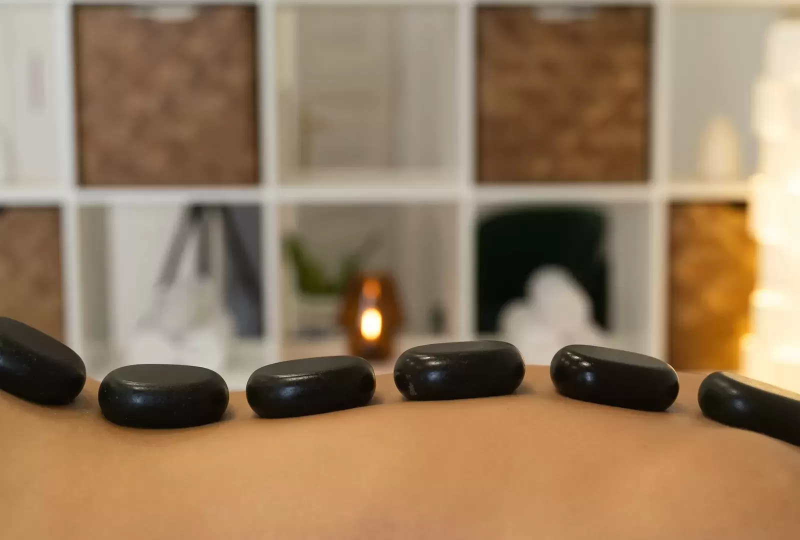 Những viên đá bazan đen nhẵn xếp dọc lưng khách trên giường massage