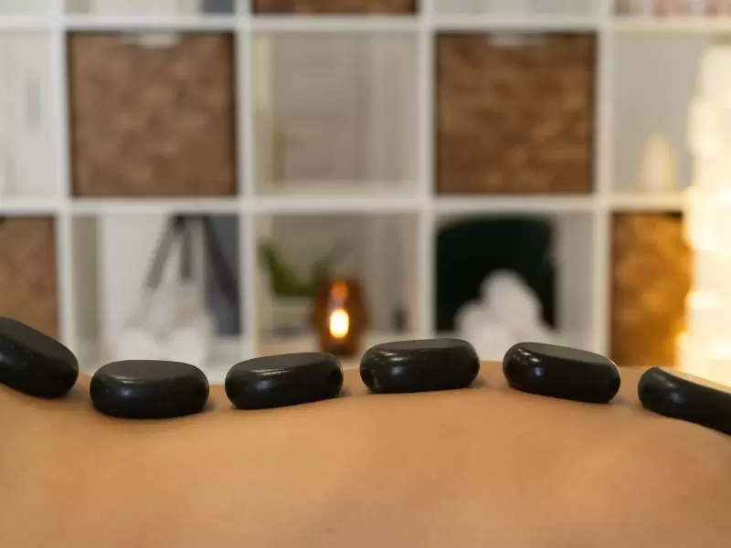Những viên đá bazan đen nhẵn xếp dọc lưng khách trên giường massage