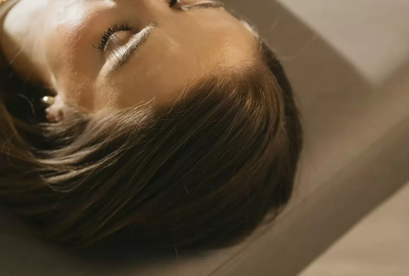 Người phụ nữ nằm nghỉ trên giường trị liệu, lưng phủ khăn trắng, ánh sáng dịu trong phòng