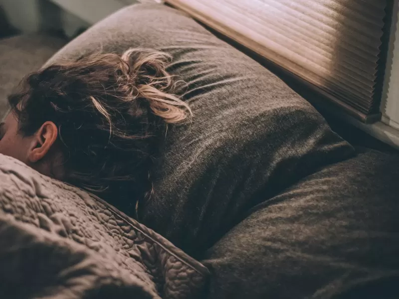 Tách trà ấm và ngọn đèn ngủ vàng dịu trên chiếc bàn nhỏ cạnh giường