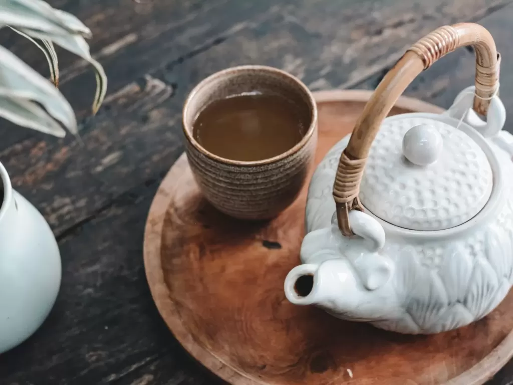 Ấm trà gốm trắng và chén trà trên khay gỗ ở sảnh trà