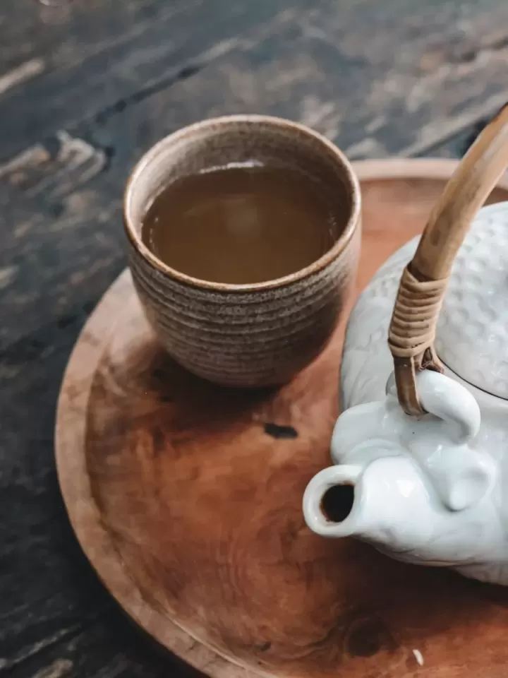Ấm trà gốm trắng và chén trà trên khay gỗ ở sảnh trà