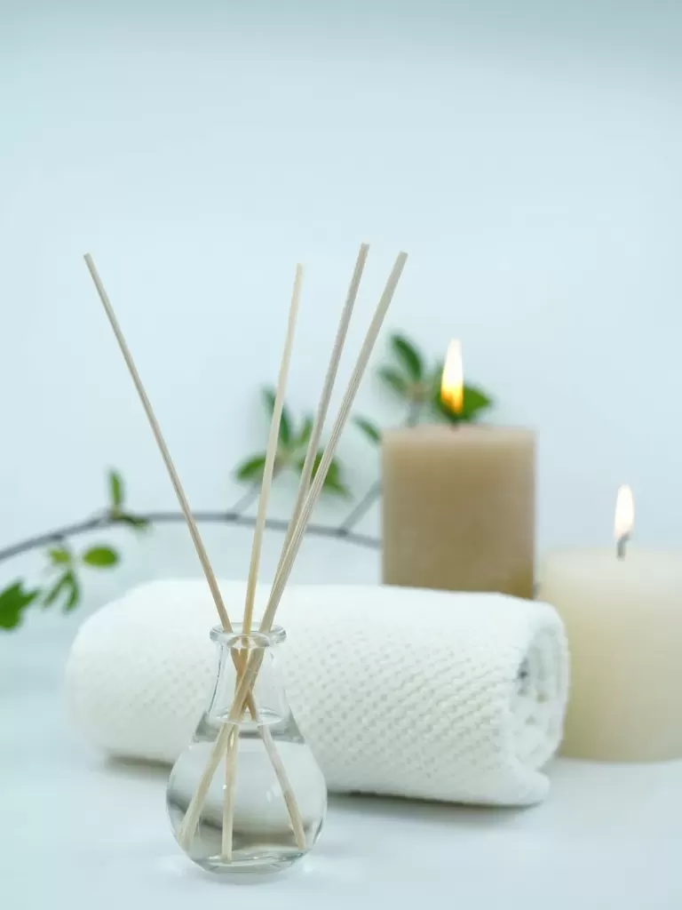 Que khuếch tán hương, khăn trắng cuộn tròn và hai ngọn nến