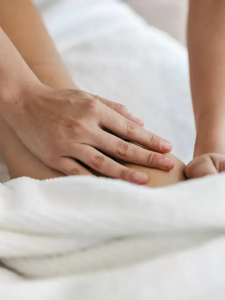 Hai bàn tay kỹ thuật viên massage chân khách trên khăn trắng