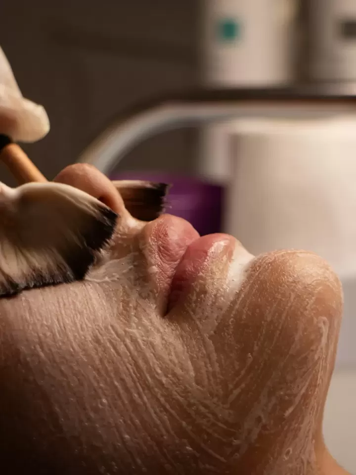 Cọ mềm thoa lớp kem trắng lên da mặt khách trong phòng chăm sóc da