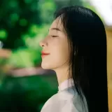 Chân dung Lương Thảo Vy, tóc dài, áo trắng, đứng giữa vườn cây