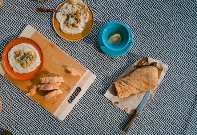 Bữa sáng dã ngoại với bánh mì, món chấm và tách xanh trên thớt gỗ