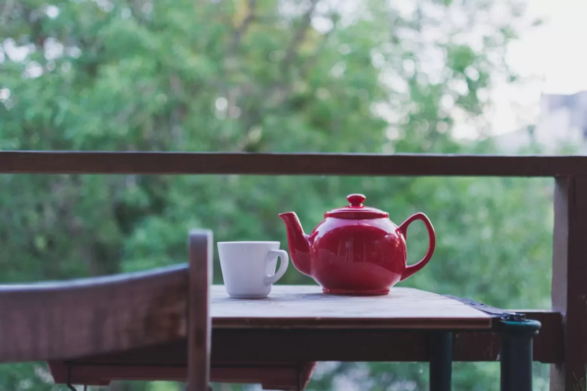 Bộ trà chiều trên bàn gỗ nhìn ra đồi trà