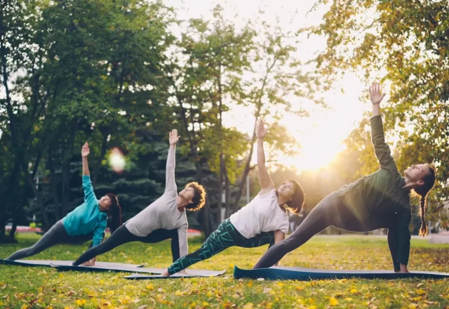 Nhóm người tập yoga trên bãi cỏ giữa rừng cây lúc nắng sớm
