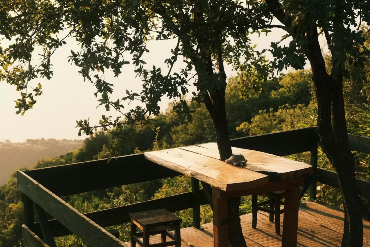 Bàn gỗ trên ban công nhìn ra tán cây lúc nắng chiều