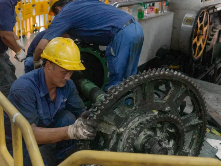 Công nhân đội mũ bảo hộ sửa cụm bánh răng máy công nghiệp