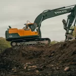 Máy đào cam trắng trên nền đất công trình