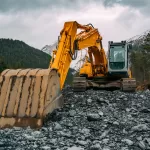 Máy đào vàng đen đang làm việc trên nền đá