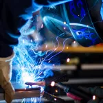 Thợ hàn đội mũ bảo hộ hàn kim loại toé lửa