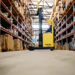 Xe nâng vàng trong kho lớn nhiều kệ hàng