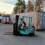 Xe nâng xanh ngọc đỗ trước bãi container