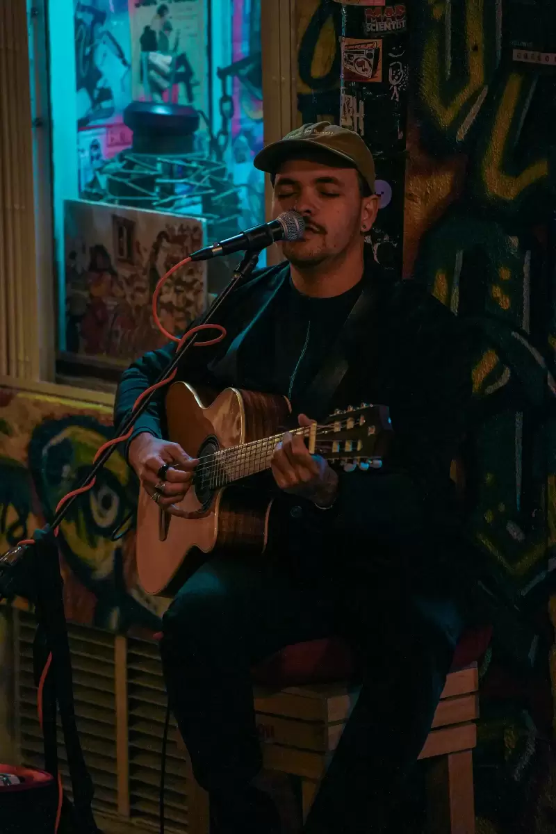 Nam nghệ sĩ vừa đàn guitar vừa hát trước micro