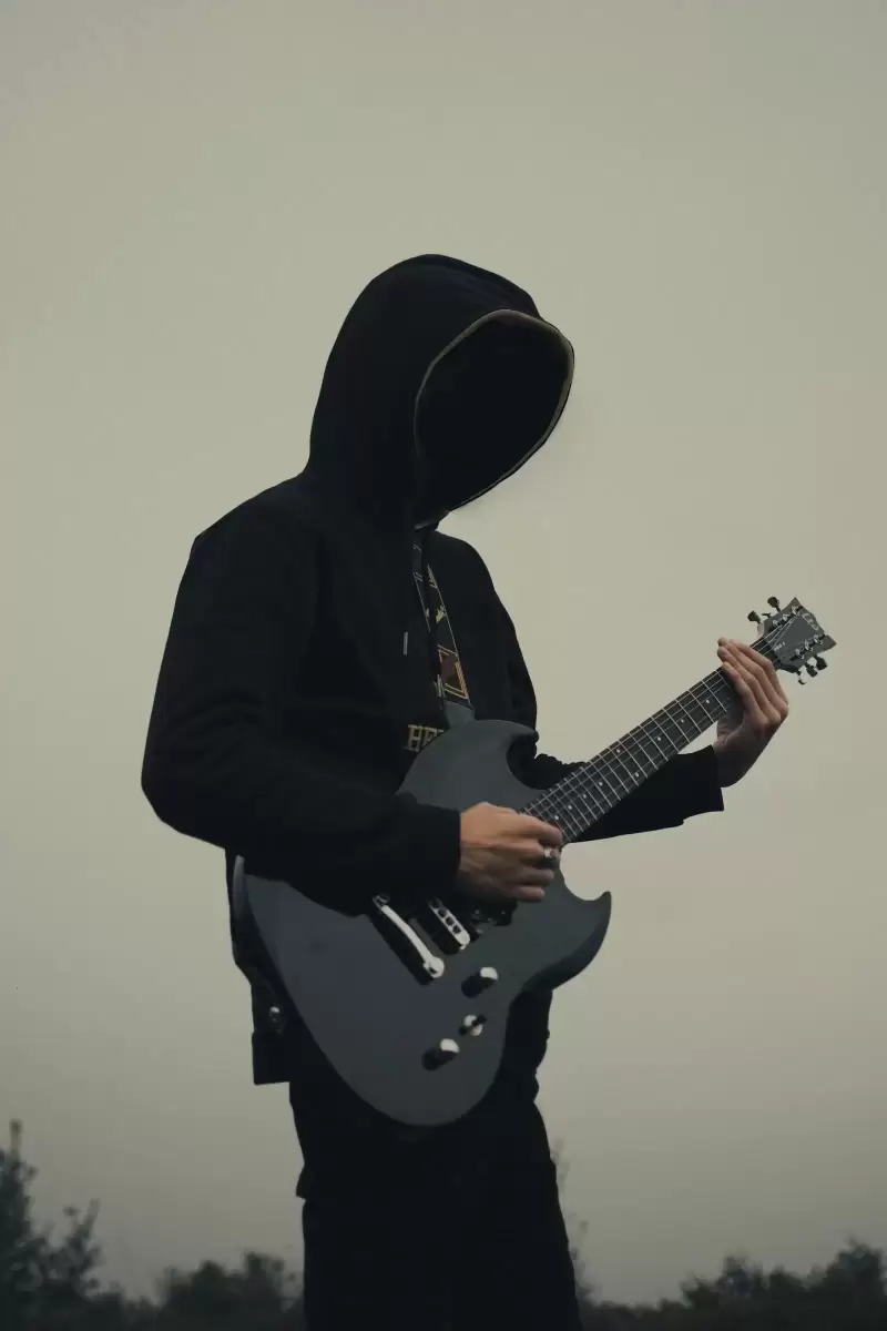 Chàng trai trẻ mặc áo hoodie chơi guitar