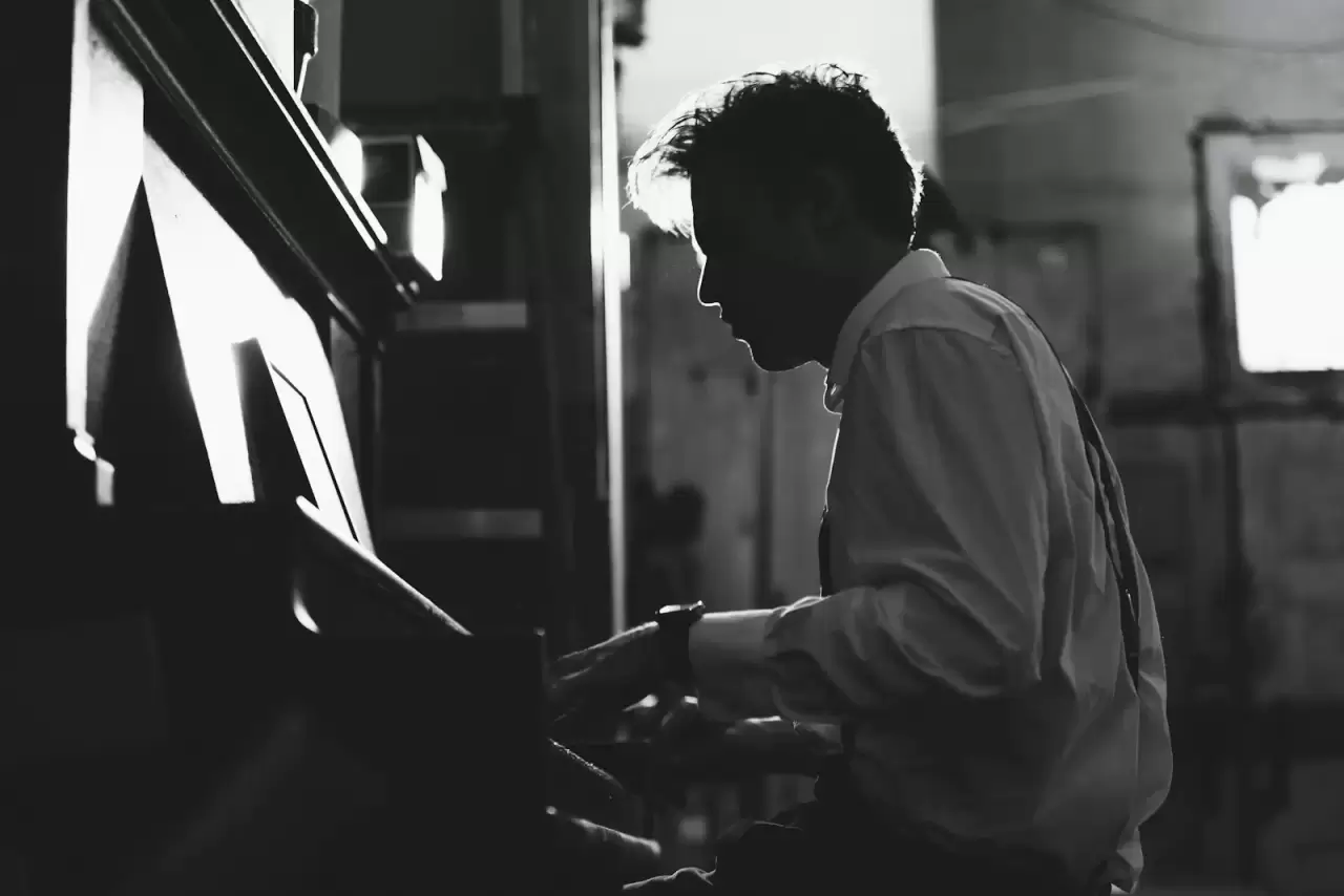 Nam nghệ sĩ nghiêng mặt chơi piano đen trắng