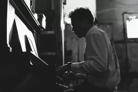 Nam nghệ sĩ nghiêng mặt chơi piano đen trắng