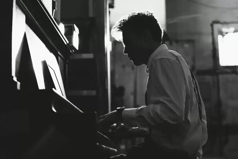 Nam nghệ sĩ nghiêng mặt chơi piano đen trắng