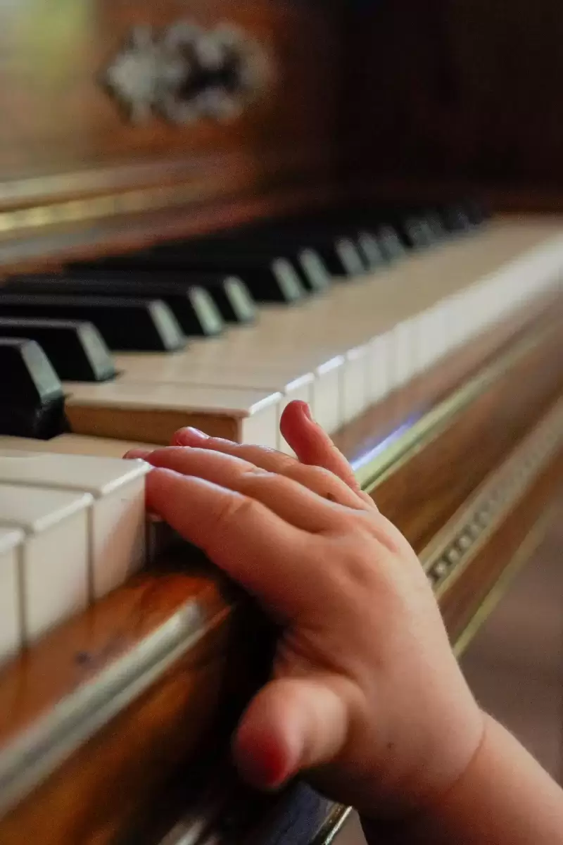 Bàn tay nhỏ của trẻ em đặt trên phím đàn piano