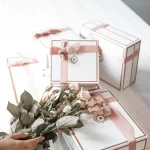 Những hộp quà trắng viền hồng cạnh bó hoa khô