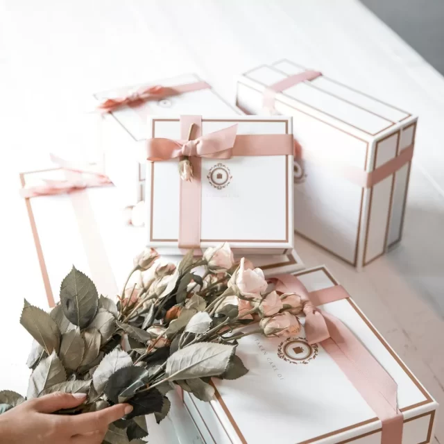 Những hộp quà trắng viền hồng cạnh bó hoa khô
